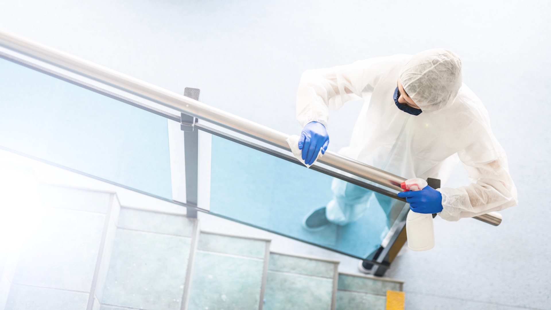 man disinfecting stair railings